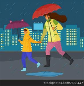 Family mother and son hurry at urban street during rain, adult woman and boy teenager with umbrellas, people wearing boots, running at puddles, night time buildings with light in windows at background. Family mother and son hurry at urban street during rain at night, adult woman and boy with umbrellas