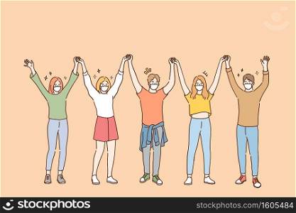 Friendship and having fun during COVID-19 pandemic concept. Group of young positive friends in protective medical face masks standing and holding raised hands in team during pandemic illustration . Friendship and having fun during COVID-19 pandemic concept