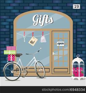 Gifts shop s facade of blue brick.. Gifts shop s facade of blue brick. Bike with gift boxes in basket and birdcage with roses at the fore . Key, sashe and postcard in the window. Vector illustration eps 10.
