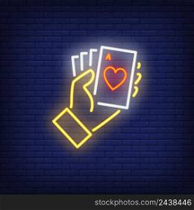 Hand holding ace cards neon sign. Heart, poker, gambler. Night bright advertisement. Vector illustration in neon style for gambling, casino and poker club