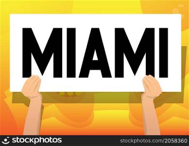 Hand holding banner with Miami text on white paper. Man showing billboard.
