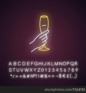 Hand holding wine glass yellow neon light icon. Champagne stemware. Glassful of alcohol drink. Wine service. Celebration. Glowing sign with alphabet, numbers and symbols. Vector isolated illustration