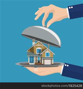 Hand opens serve cloche with house inside. present concept. vector illustration in flat design. Hand opens serve cloche with house inside.