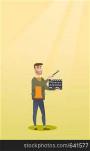 Happy caucasian man holding camera slate for the filming. Smiling hipster man holding open clapperboard. Cheerful man holding blank movie clapperboard. Vector flat design illustration. Vertical layout. Smiling man holding an open clapperboard.