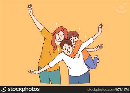 Happy family of mom, dad and child put arms to sides, pretending to be airplanes, and posing for group portrait. Cheerful family having fun and smiling looking at camera to share good mood. Happy family of mom, dad and child put arms to sides, pretending to be airplanes