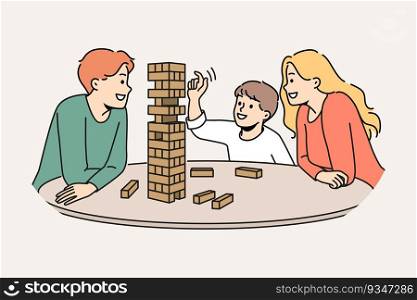 Happy family plays jenga with child enjoying board game and developing fine motor skills in baby. Satisfied boy plays jenga with parents pulling wooden block out of unstable tower.. Happy family plays jenga with child enjoying board game and developing fine motor skills in baby