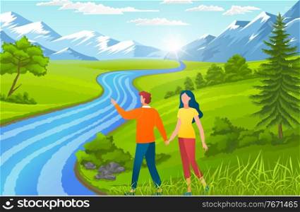 Happy in love couple holding hands and walking near river. Man show mountains to girl. People walking at nature, green grass near foot mountains. Young guy spend leisure time with girlfriend outdoors. Happy in love couple holding hands and walking near river, man show mountains to girl, summertime