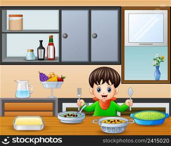 Happy little boy holding spoon and fork eating at the table 