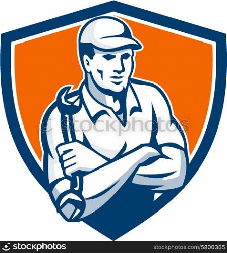 Illustration of a mechanic wearing hat holding spanner wrench arms crossed set inside shield crest on isolated background done in retro style.. Mechanic Holding Spanner Arms Crossed Shield Retro