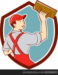 Illustration of a plasterer masonry tradesman construction worker standing with trowel looking to the side viewed from rear set inside shield crest on isolated background done in cartoon style. . Plasterer Masonry Trowel Shield Cartoon