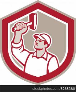 Illustration of a union worker wielding a hammer looking up set inside shield crest shape done in retro style.. Union Worker Wielding Hammer Shield Retro