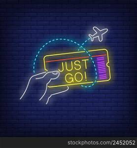 Just Go neon lettering and hand holding flight ticket. Tourism, vacation and travel design. Night bright neon sign, colorful billboard, light banner. Vector illustration in neon style.