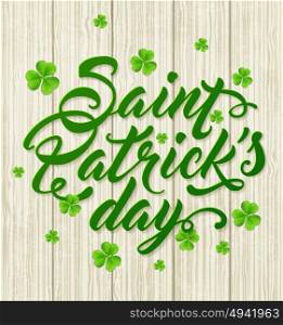 Lettering and green clover leaves on a wooden background. Greeting card for St. Patrick&rsquo;s Day