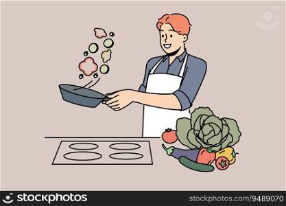 Man cook stands at stove and prepares romantic dinner of fried vegetables for beloved woman. Chef cook guy throws food on pan demonstrating skills of professional culinary specialist. Man cook stands at stove and prepares romantic dinner of fried vegetables for beloved woman