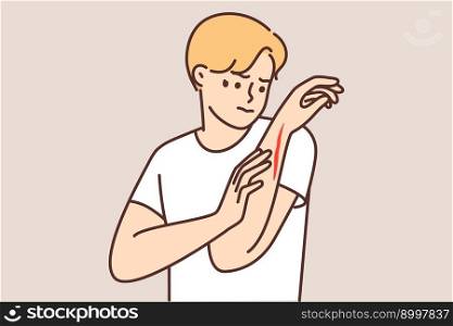 Man examines hand with deep cut or wound received after accident at work. Guy with bleeding wound on body needs bandages and anti-infective treatment to protect himself from ingress of bacteria . Man examines hand with deep cut or wound received after accident at work