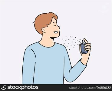 Man holds bottle of perfume and uses it before date with girl to exude good scent. Young guy in casual t-shirt closing eyes, applies perfume or deodorant to body to get rid of bad smell.. Man holds bottle of perfume and uses it before date with girl to exude good scent