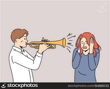 Man plays trumpet near woman covering ears, for concept trumpeter lack musical talent. Guy who wants to become professional musician learns to play compositions on trumpet and interferes with others. Man plays trumpet near woman covering ears, for concept trumpeter lack of musical talent