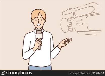 Man reporter with microphone stands near professional video camera filming TV documentary or entertainment show. Young guy working as reporter on television channel smiles and gesticulates. Man reporter with microphone stands near professional video camera filming TV documentary 
