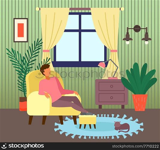 Man sitting at armchair in living room near window. Guy enjoy leisure time, like spend time at home. Cat relaxing at carpet. Indoor recreation at home. Chest of drawers with lamp in room, houseplant. Man sitting at armchair in living room near window, guy enjoy leisure time, like spend time at home