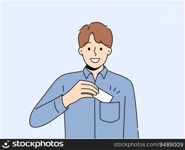 Man takes out business card from pocket to exchange contacts with potential partner or buyer and looks into camera with smile. Business guy in blue shirt wants to share contacts with new acquaintances. Man takes out business card from pocket to exchange contacts with potential partner or buyer