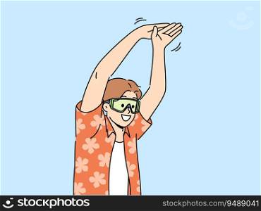 Man tourist stands in pose of swimmer wanting to dive into pool or sea during summer vacation. Young happy guy in goggles for swimming and summer shirt getting ready to jump in sea water. Man tourist stands in pose of swimmer wanting to dive into pool or sea during summer vacation