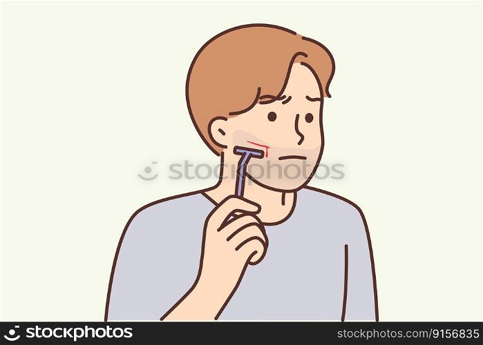 Man using manual razor cuts himself during morning skincare routine. Clumsy young guy who shaves with manual razor inflicted bleeding wound with blade due to carelessness or inexperience . Man using manual razor cuts himself during morning skincare routine due to carelessness 