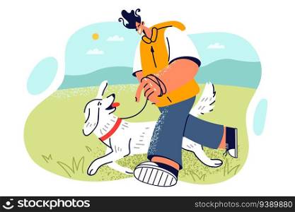 Man walks dog in park, leading pet on leash and enjoying warm weather and sunny day. Smiling teenager guy walking on grass with friendly puppy for concept of love for dog or pet care. Man walks dog in park, leading pet on leash and enjoying warm weather and sunny day.