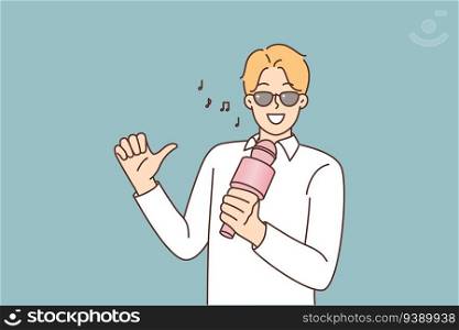 Man with microphone sings in karaoke, performing songs of favorite pop group and relaxing after hard working week. Male singer or wakal teacher sings and looks confidently at screen. Man with microphone sings in karaoke, performing songs of favorite pop group an looks at screen
