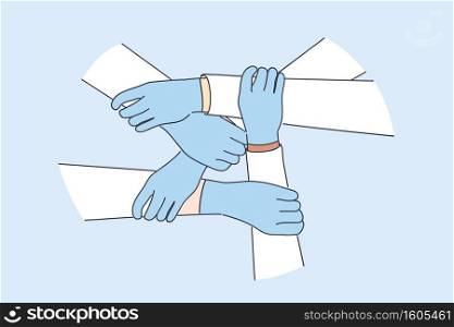 Medical teamwork, health worker unity concept. Hands of doctors in protective gloves holding each other global healthcare partnership and uniting efforts against pandemic of COVID-19. Medical teamwork, health worker unity concept