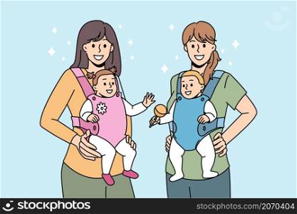 Modern mothers carrying equipment concept. Two young positive women mothers standing holding their babies in slings for outdoor walks vector illustration . Modern mothers carrying equipment concept.