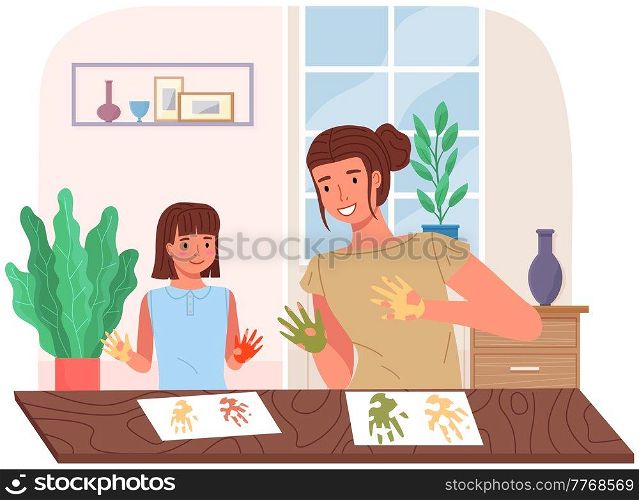 Mother and daughter painting at home. Mom and child study or playing together. Woman teaches girl to draw. Happy family pastime. People paint hands with dye and leaves traces of palms on paper. People paint hands with dye and leaves traces of palms on paper. Mother and daughter painting