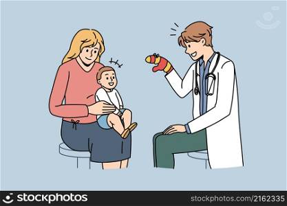 Pediatrician working with babies concept. Young smiling man pediatrician sitting and playing with small baby on mothers knees with mitten vector illustration . Pediatrician working with babies concept