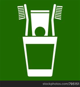 Plastic cup with brushes icon white isolated on green background. Vector illustration. Plastic cup with brushes icon green
