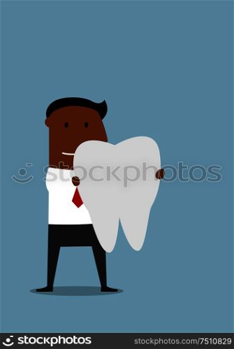 Pleasant smiling cartoon african american businessman standing with a large white healthy tooth in hands. Health insurance or dentistry theme design usage. Businessman with a large white tooth