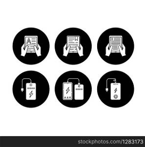 Portable electronic devices glyph icons set. Power bank. Portable battery. Pocket charging gadget. Hands holding e-readers. Digital reading. Vector white silhouettes illustrations in black circles