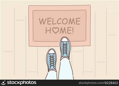 Rug with inscription welcome home on threshold near entrance to apartment and feet of man in boots. Top view of porch with rug with word welcome to create cozy and welcoming atmosphere . Rug with inscription welcome home on threshold near entrance to apartment and feet of man in boots
