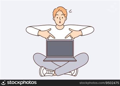 Shocked man with laptop pointing fingers at screen recommending visiting interesting website or downloading software. Guy sits with laptop on knees offering to buy cool computer at bargain price. Shocked man with laptop pointing fingers at screen recommending visiting interesting website