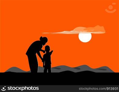 Silhouette of mother and son standing on the mountain watching the sunset.
