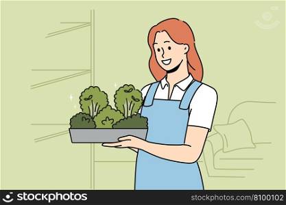 Smiling woman in apron holding box with greenery in hands. Happy girl with microgreen container work in greenhouse. Vector illustration. . Smiling woman with microgreen container in hands 