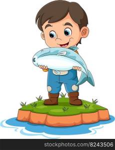 The boy is catching the big dead fish in the river while smiling and happy