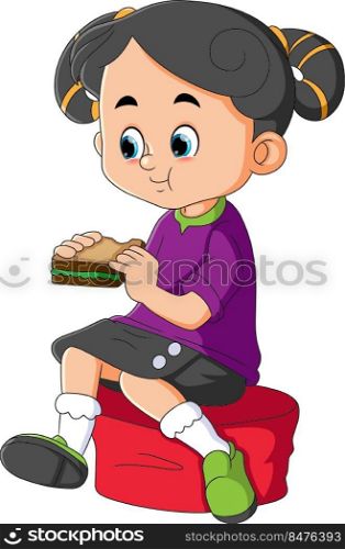 The little girl is sitting on the chair while eating a sandwich
