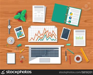 Top view of wood workplace with laptop, calculator, smartphone, stationery and documents with charts and graphs