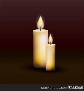 Two burning candles on a dark background