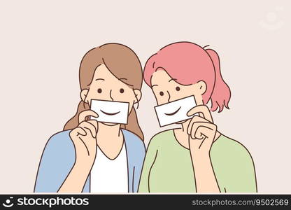 Two women with fake smiles hold papers with drawn emotions and pretend to be happy. Concept of hypocrisy and psychological problems causing desires to appear successful and happy or friendly. Two women with fake smiles hold papers with drawn emotions and pretend to be happy