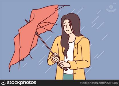Wet woman stands with broken umbrella in heavy rain, and is sad because of cold and strong wind. Upset girl walking down street during storm and autumn rain needs waterproof clothes. Wet woman stands with broken umbrella in heavy rain, and is sad because of cold and strong wind