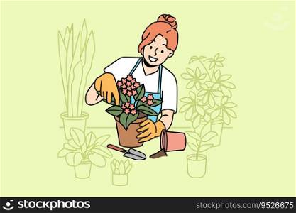 Woman florist takes care of home plants and holds flower pot with blooming vio≤t standing≠ar tab≤. Girl in apron enjoys job as florist, and makes career as sa≤sperson in store or greenhouse. Woman florist takes care of home plants and holds flower pot with blooming vio≤t