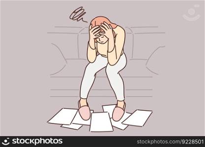Woman frustrated with financial problems, sits with head bowed over papers scattered on floor near sofa. Girl is experiencing financial difficulties, needing government subsidies or bankruptcy. . Woman frustrated with financial problems, sits with head bowed over papers scattered on floor