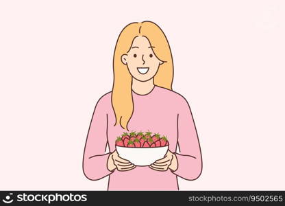 Woman holds plate of strawberries and smiles, offers to try fresh berries and farm fruits. Girl with smile looks at screen recommending eating organic strawberries containing antioxidants. Woman holds plate of strawberries and smiles, offers to try fresh berries and farm fruits