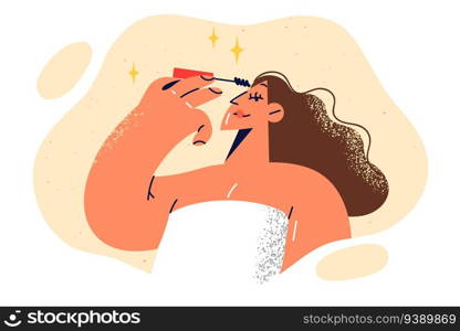Woman in towel does makeup, applying shadow on eyelashes during morning routine and preparation for work day. Girl does makeup using high-quality cosmetics to prepare for party or going on date. Woman in towel does makeup, applying shadow on eyelashes during morning routine.