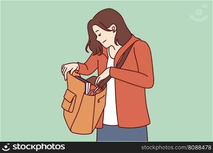 Woman looks into large bag hanging on shoulder in search of wallet or phone lost in handbag. Tourist girl with handbag dressed in casual clothes is trying to find lost or stolen personal items. . Woman looks into large bag hanging on shoulder in search of wallet or phone lost in handbag